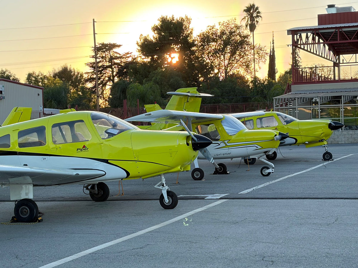 Yellow Piper and Cessna 162 training airplanes parked on the Van Nuys Airport ramp at sunset