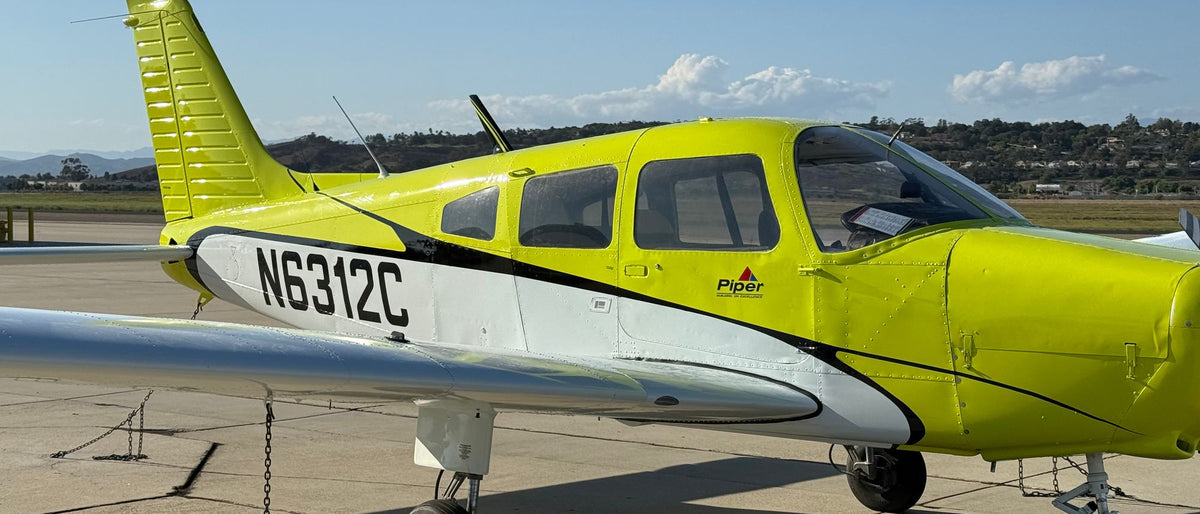 Side view of Piper Warrior N6312C on a sunny ramp, cabin and cowling in view