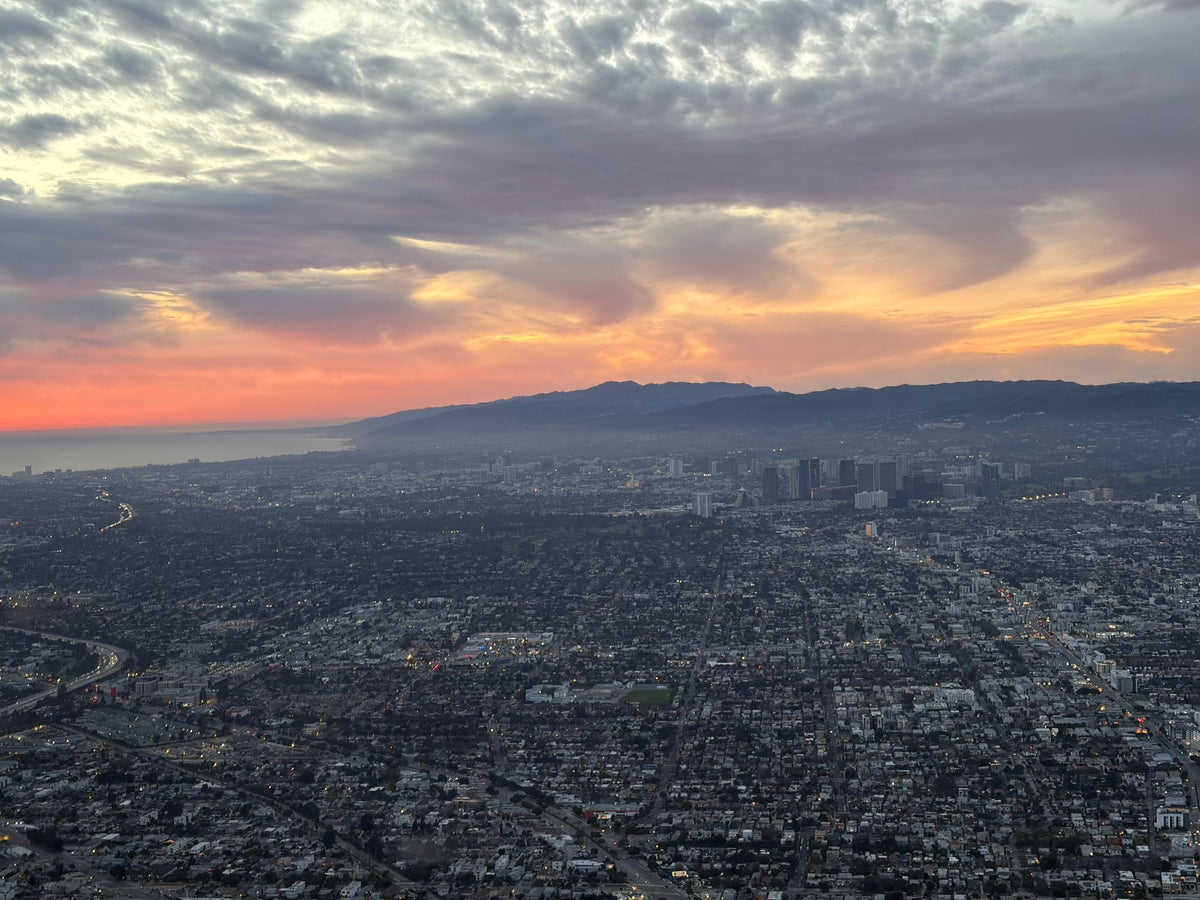 Aerial dusk view of West Los Angeles with Century City towers, the mountains and the curve of Santa Monica Bay
