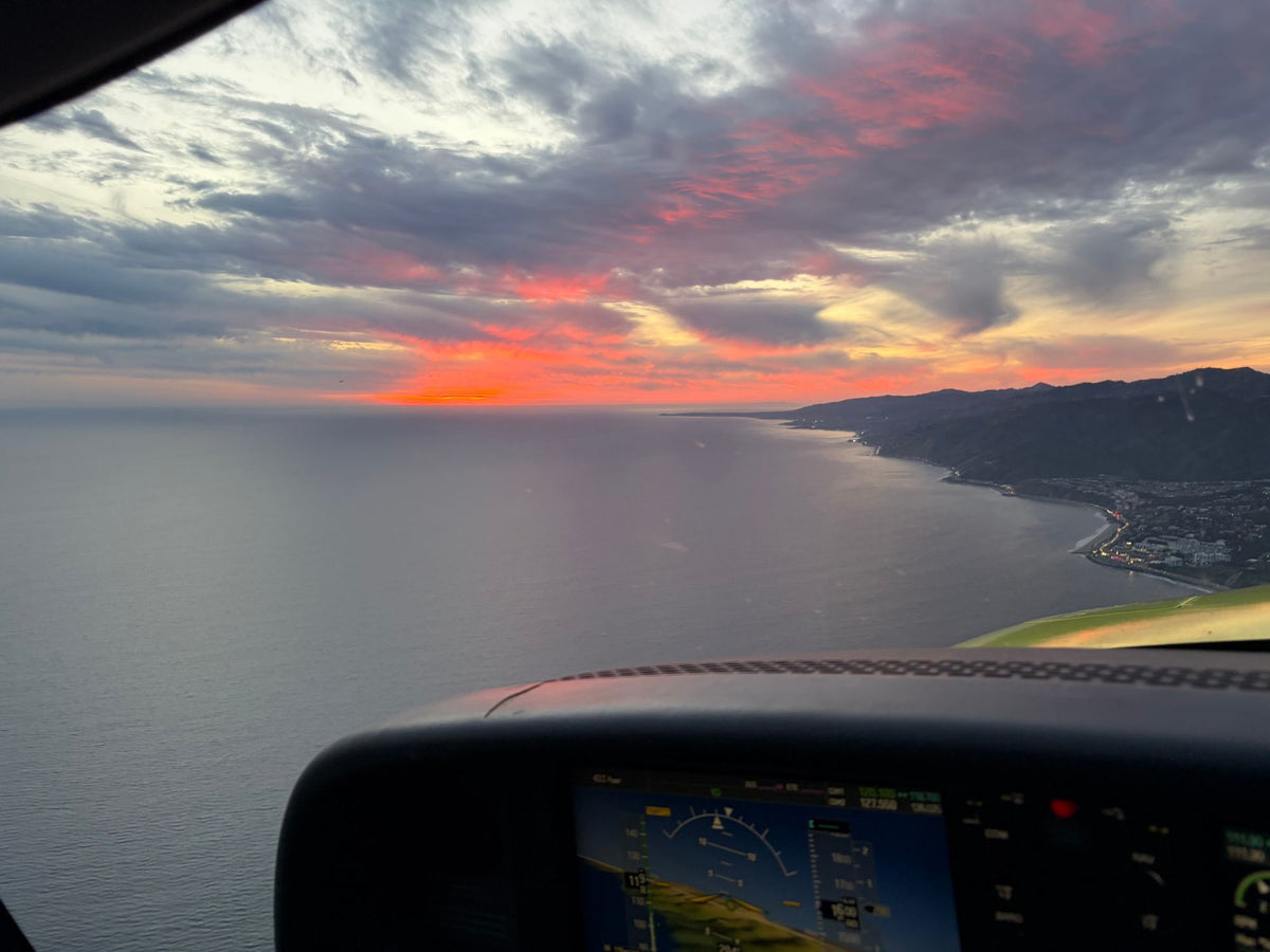The Pacific Palisades coast at sunset over a glass-panel glareshield