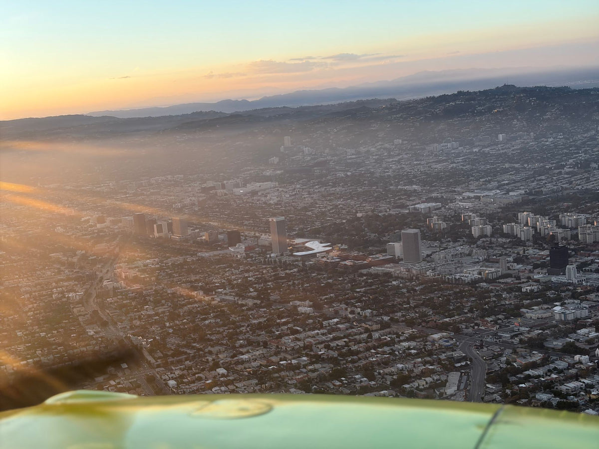 Aerial view of West Los Angeles high-rises and neighborhoods in golden haze with the Santa Monica Mountains behind