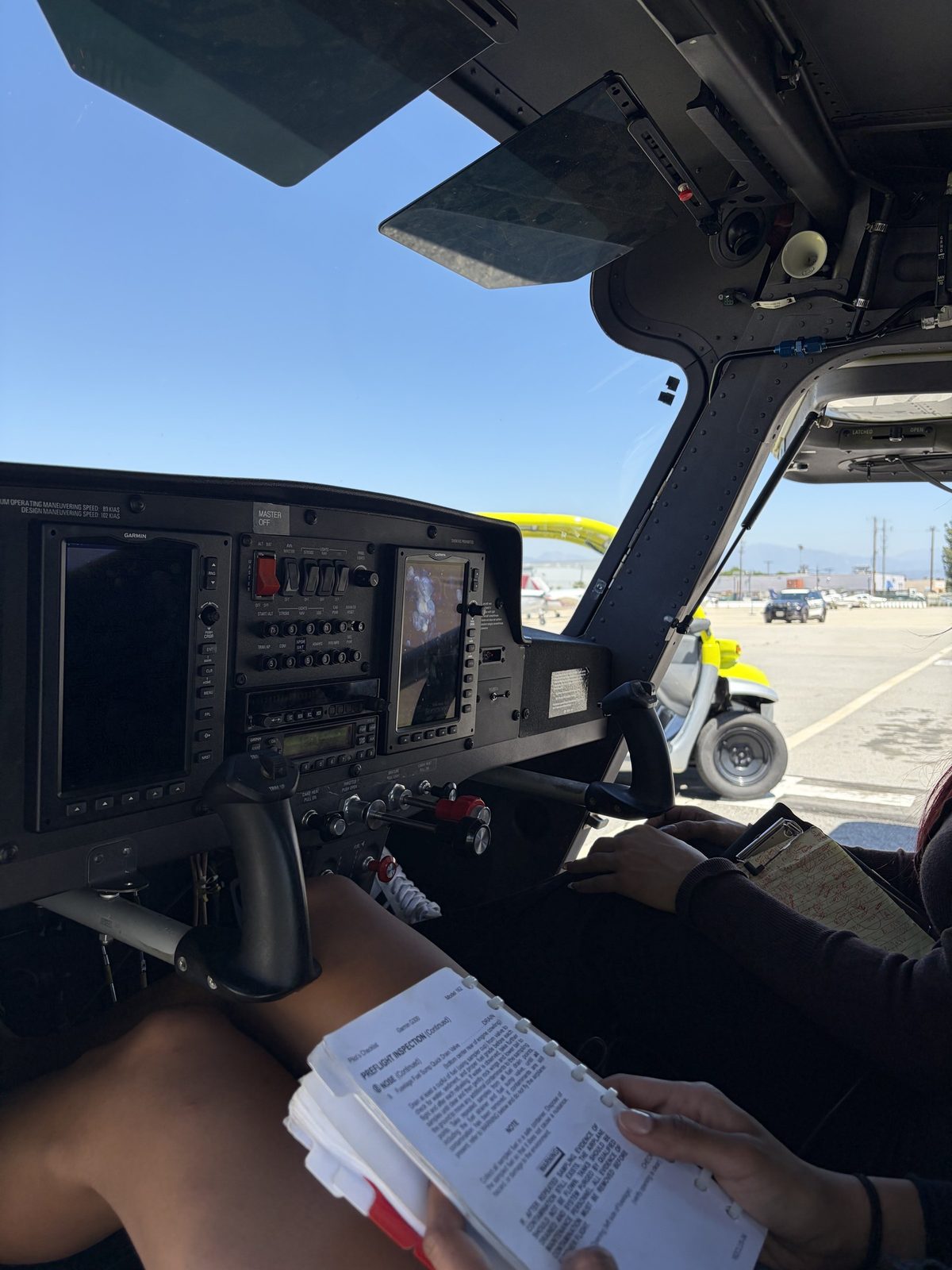 A student's hand on the Cessna 162 glass panel, holding the checklist