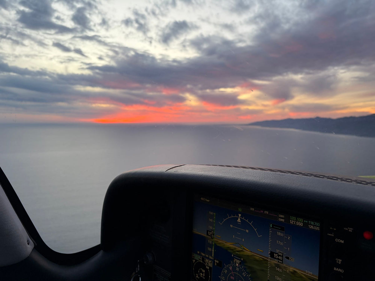 A glass cockpit panel with a sunset over Santa Monica Bay through the windshield