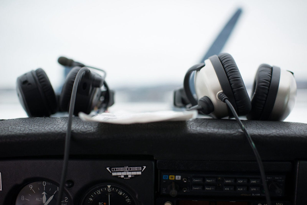 Two aviation headsets resting on the glareshield of a training airplane cockpit