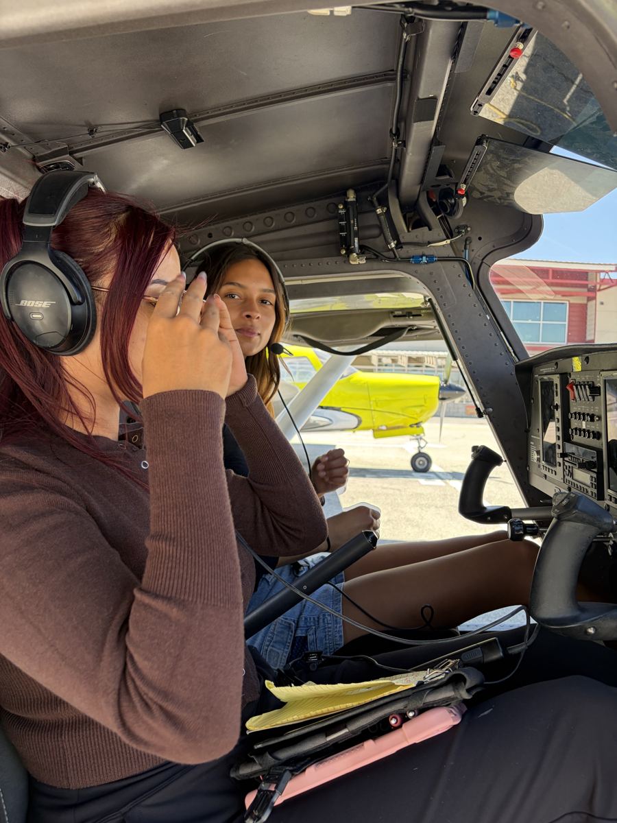 Instructor and student side by side in the cockpit of a training airplane, both in headsets