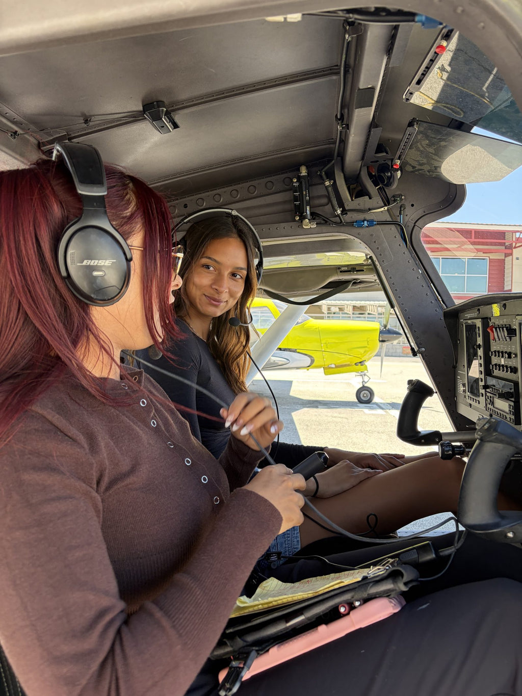 Instructor and student at the open cockpit door of a training airplane
