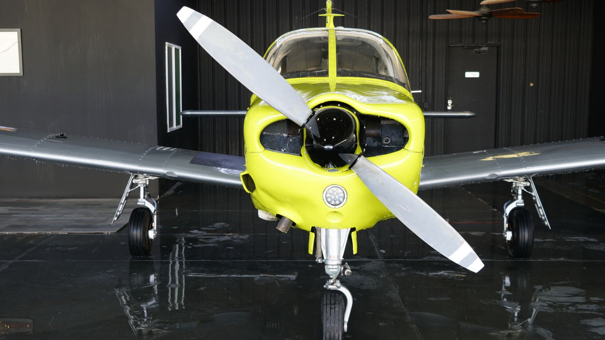 Piper Arrow head-on in a dark hangar with a reflective floor