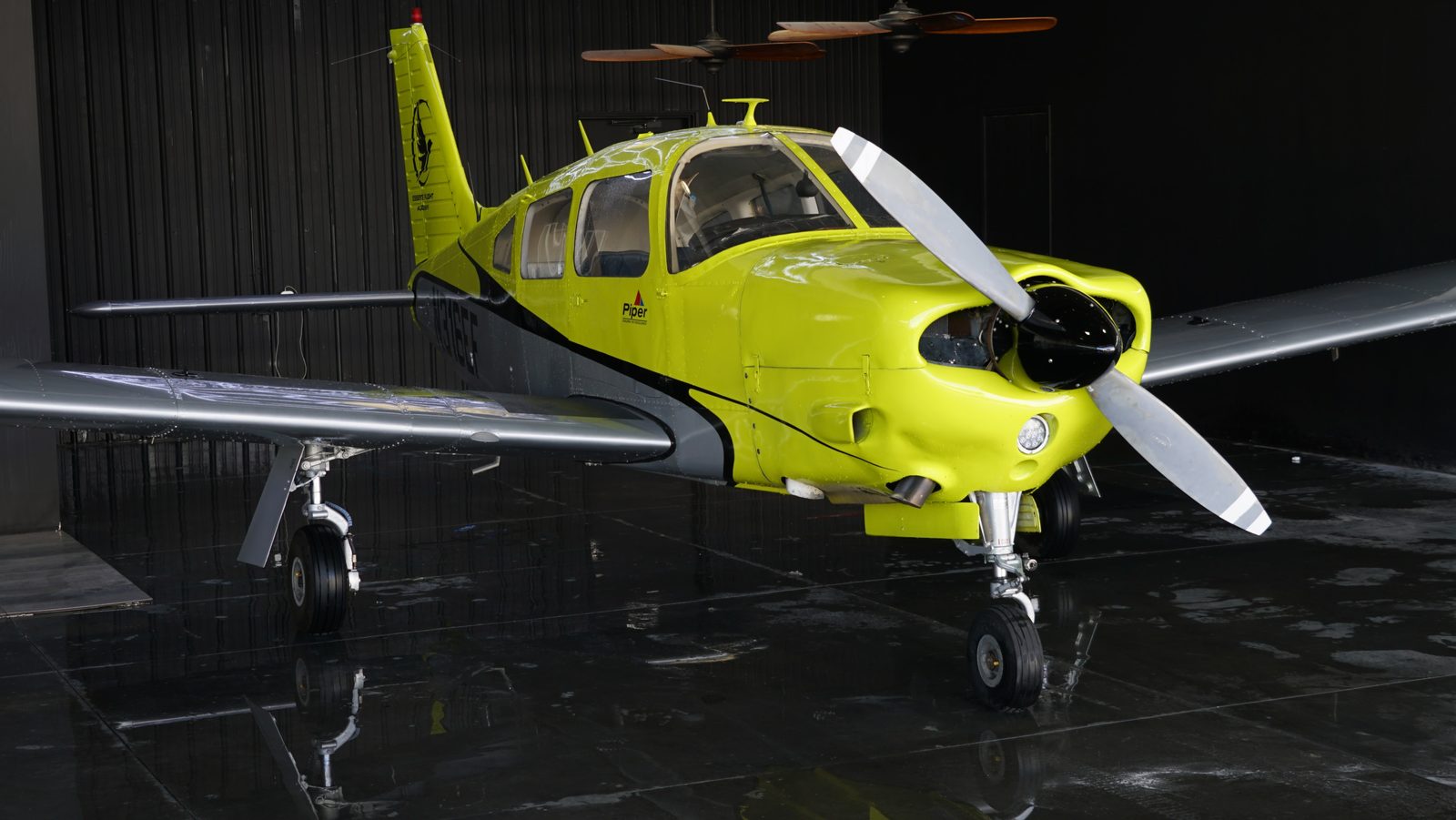Front-quarter view of a four-seat low-wing Piper trainer inside the hangar