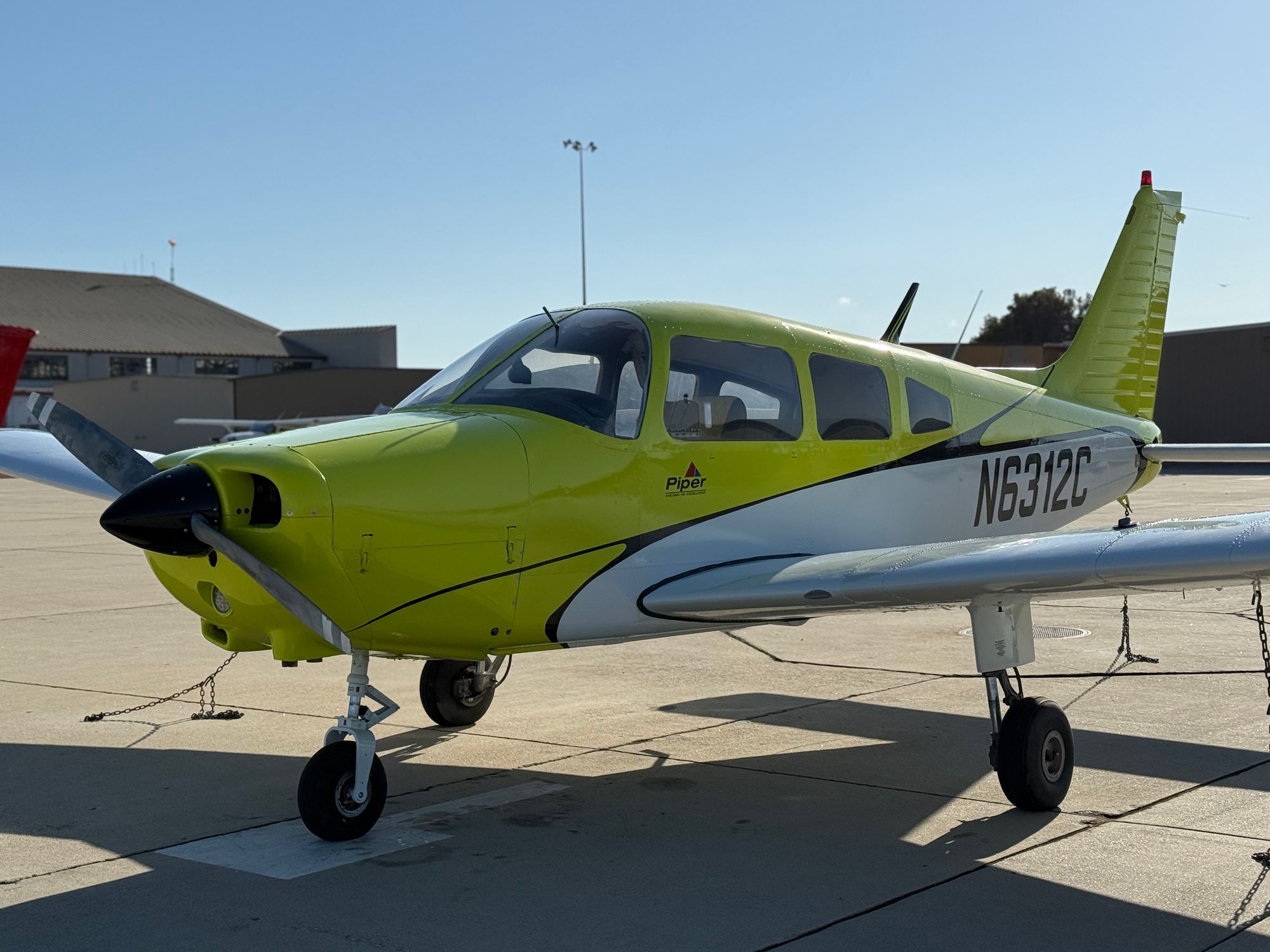 Piper Warrior N6312C, a four-seat low-wing trainer, parked on a sunny ramp